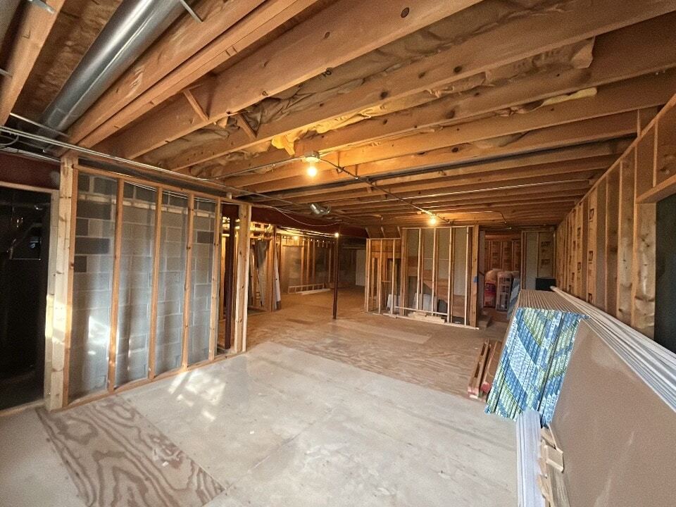 Basement renovation in progress with rooms framed below exposed floor joists