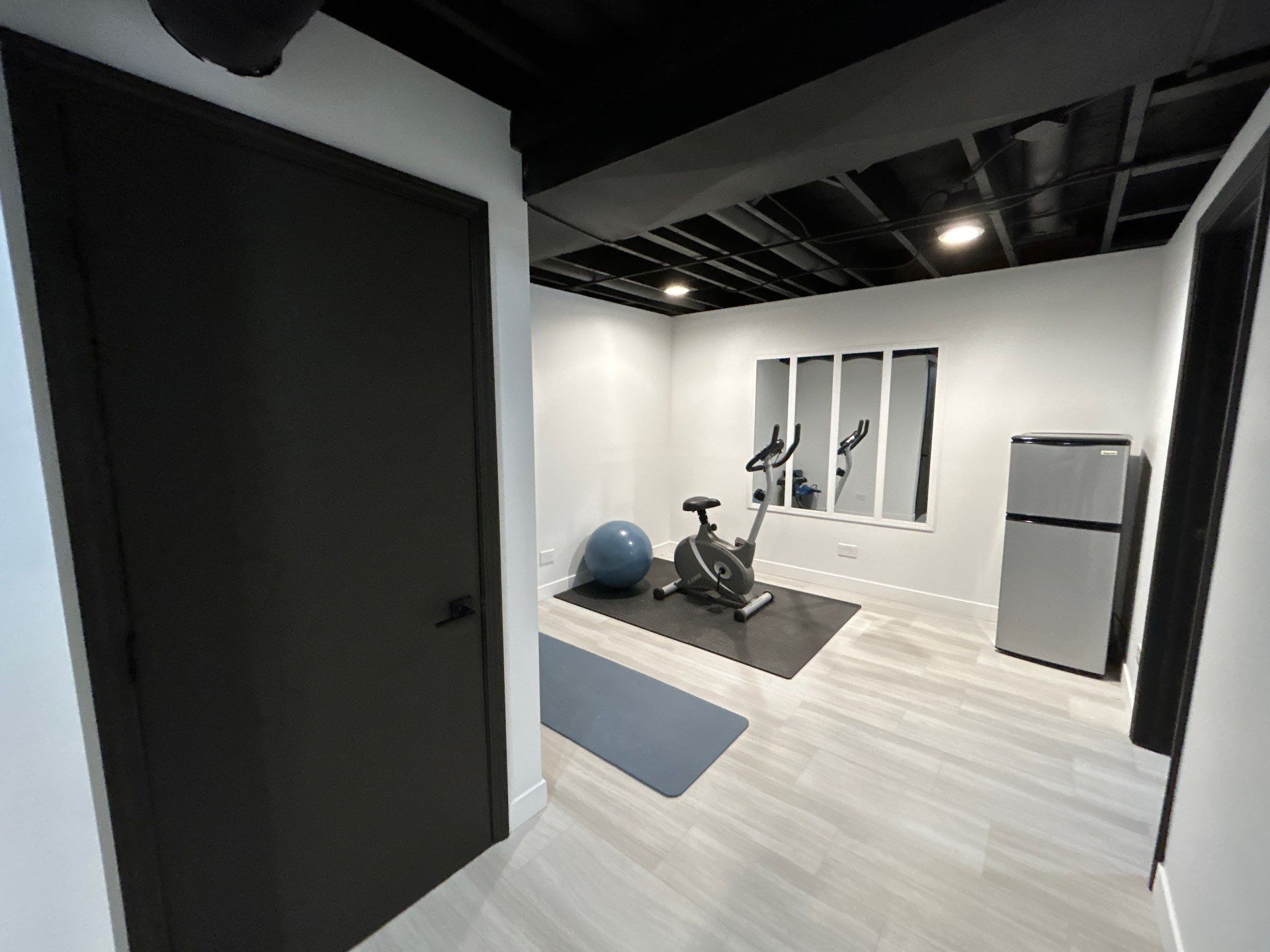 Finished J&J basement home gym viewed through a dark doorway