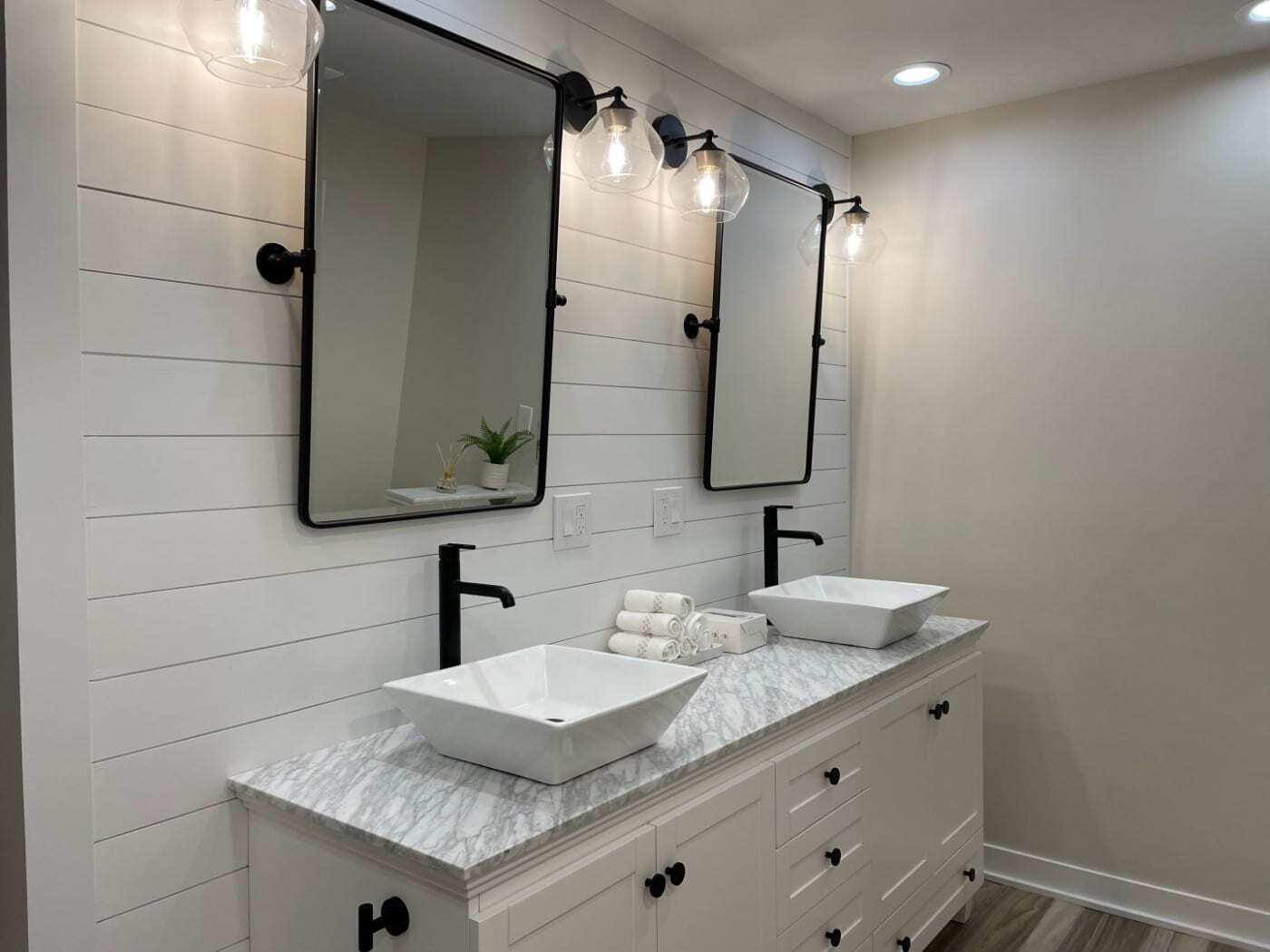 Double vanity with vessel sinks, black faucets, mirrors, and a white shiplap wall