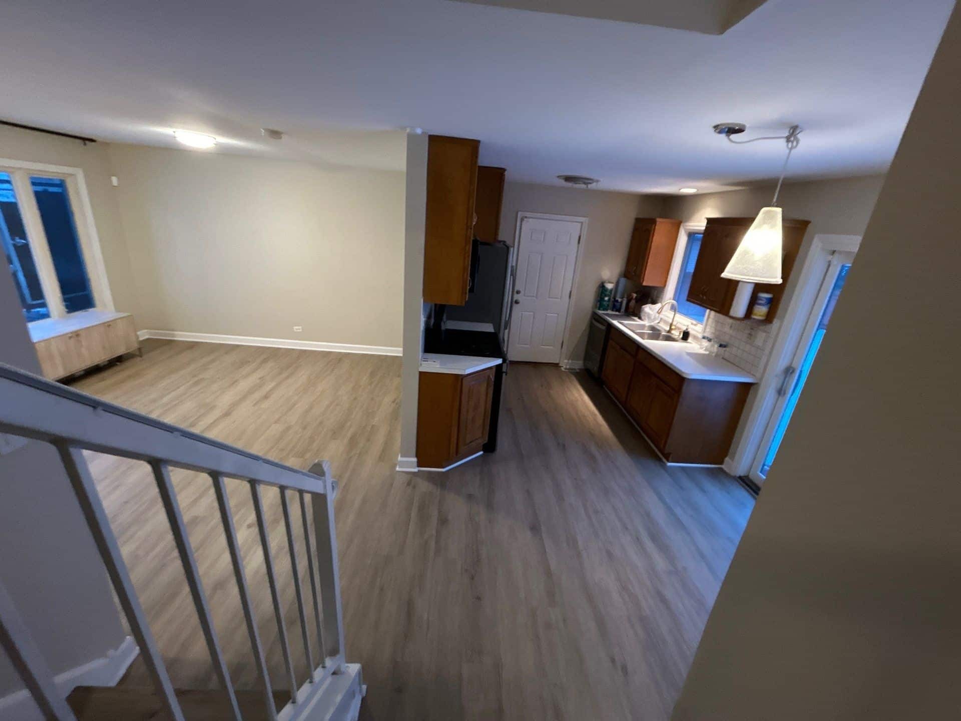 Renovated kitchen and dining space connected by continuous light wood-look flooring