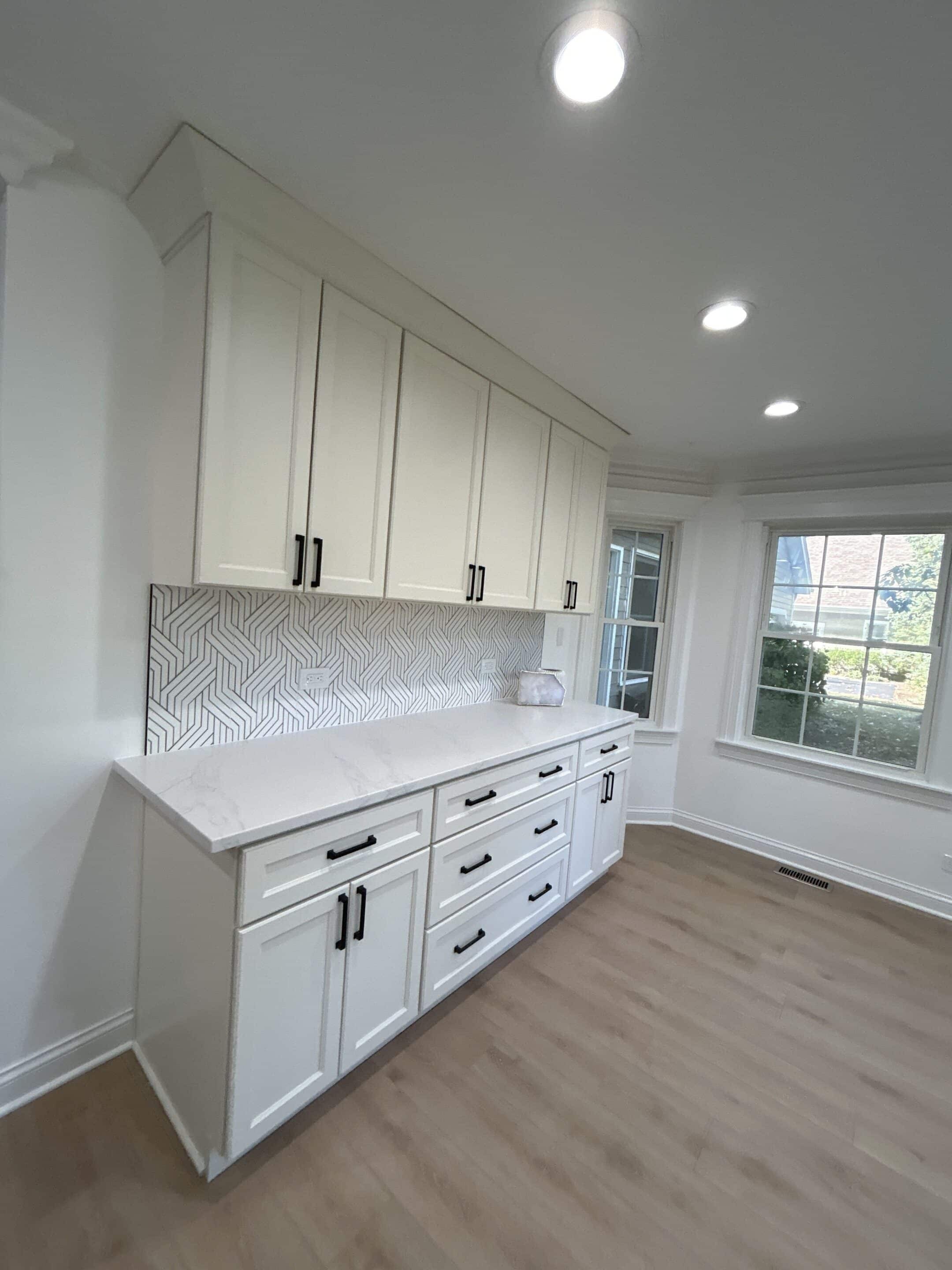 Kitchen cabinetry and backsplash detail with white drawers and black hardware