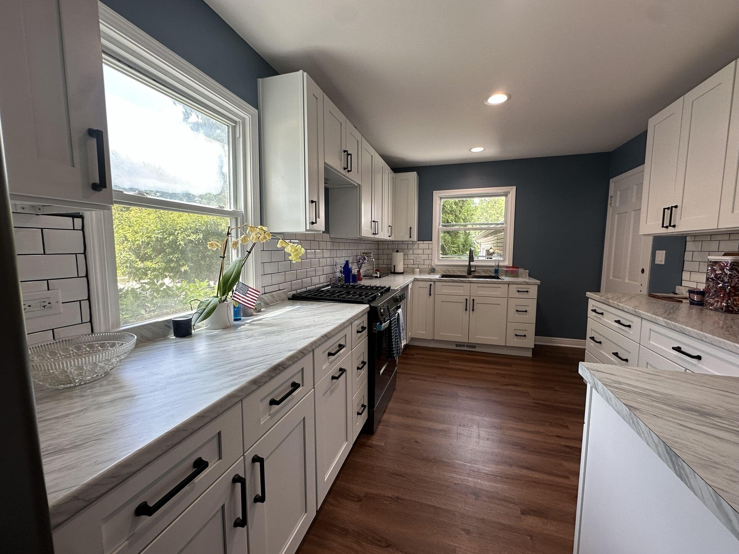 Remodeled kitchen with white shaker cabinets, stone counters, and central island